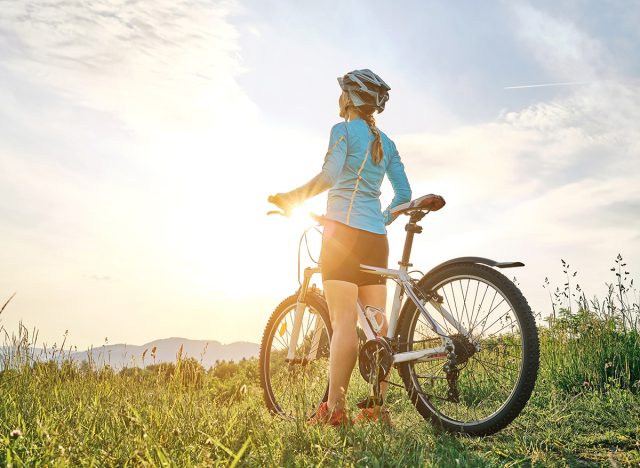Cyclist Woman riding bike in helmets go in sports outdoors on sunny day a mountain in the forest. Silhouette female at sunset. Fresh air. Health care, authenticity, sense of balance and calmness.