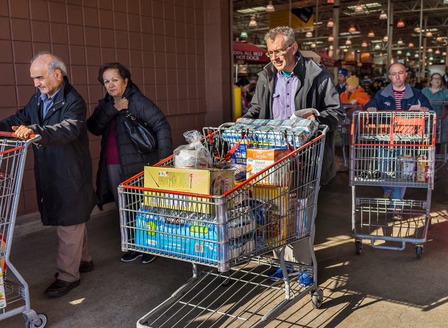 People with shopping carts filled with groceries walking out of Costco store 