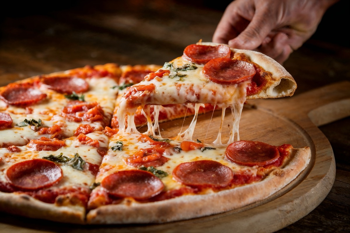 Delicious Pepperoni Pizza Slice Being Lifted From Wooden Board