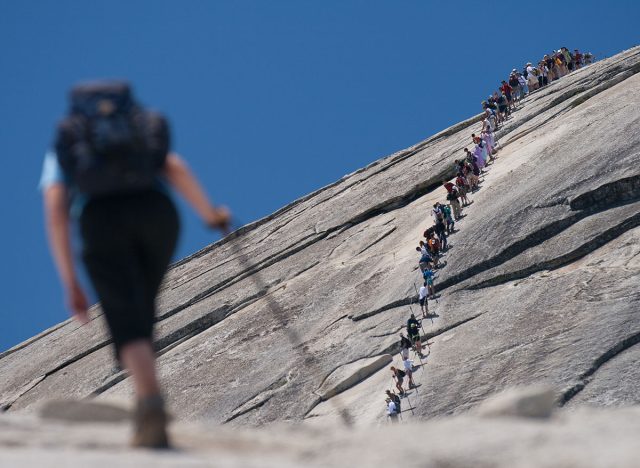 Hiker climbing on a rock, Half Dome, Yosemite Valley, Yosemite National Park, California, USA