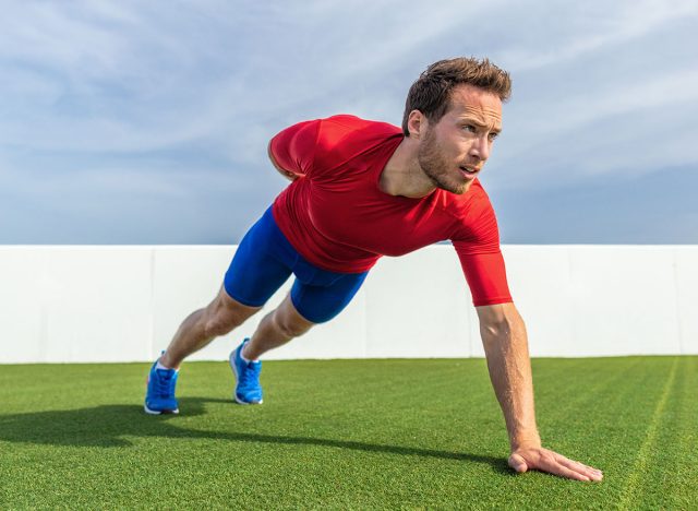 One Arm Pushup bodyweight exercise strong man working out muscles with advanced variation of push-ups. Push up training at gym.