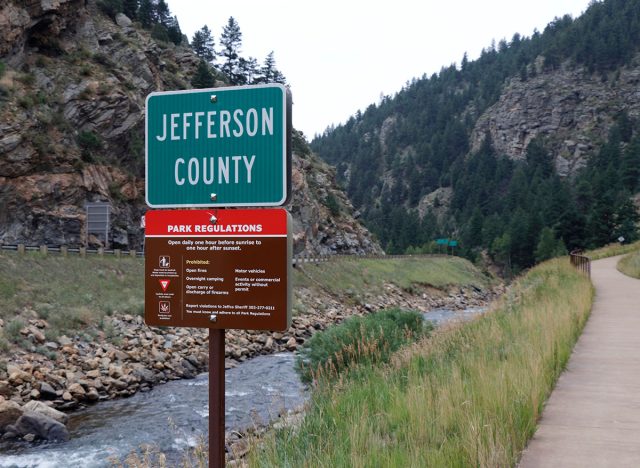 Idaho Springs, CO, USA - August 8, 2018: Scott Lancaster Memorial Trail park regulations sign along Clear Creek. Small outdoor sign in Jefferson county along Clear Creek showing rules of the park.