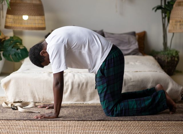 Sporty muscular young african man working out, yoga, pilates, fitness training, doing Cat Pose