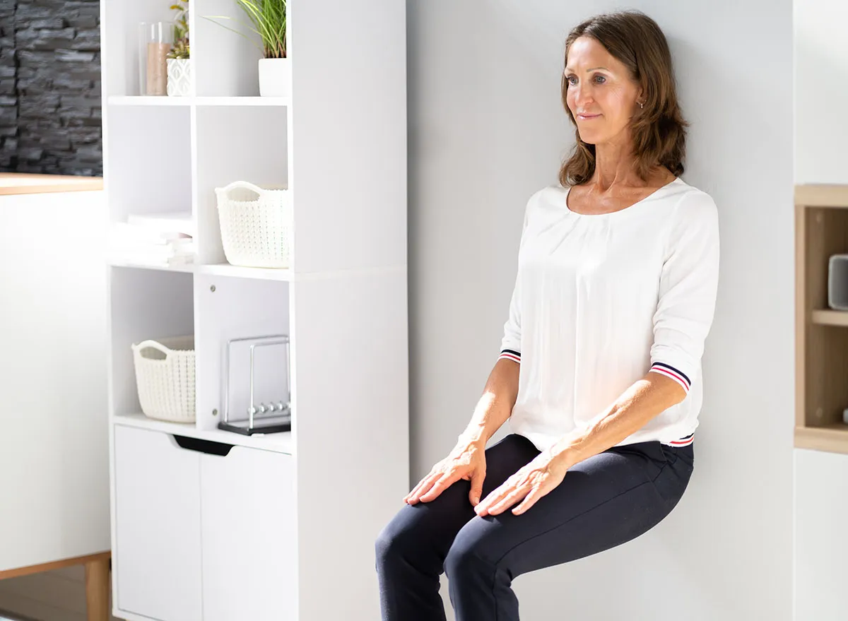 Young Businesswoman Leaning On Wall Doing Workout At Workplace