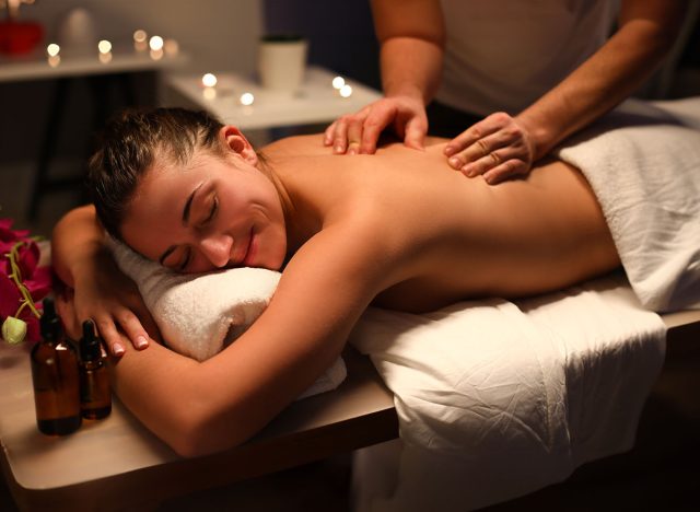 Smiling woman masseur doing back massage at spa center. Benefits of therapeutic massage for back and spine concept