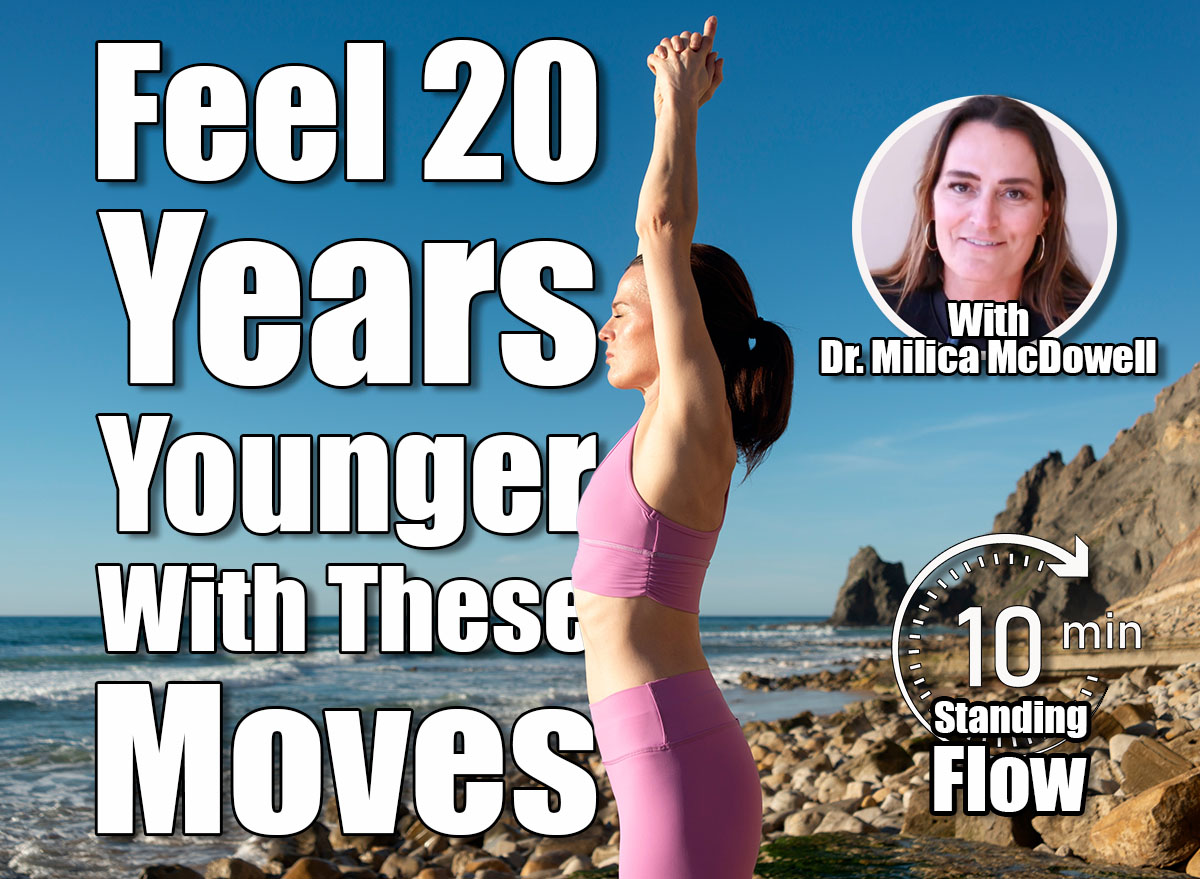 woman standing on rocks by the sea meditating and practicing yoga, arms above head, 5 Simple Standing Exercises That Make You Feel 20 Years Younger, Cover