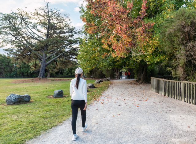 Beautiful asian woman walking and exercising in autumn park at Cornwall park, Auckland, New Zealand