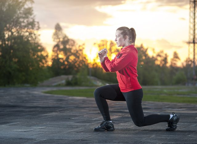 Fit woman in sportswear doing frontal lunges (squats). Fitness, workout, sport outdoors concept.