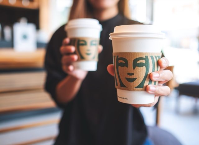 Jun 13th 2022 : Closeup of a woman holding and serving two cup of hot coffee at Starbucks coffee shop, Chiang mai Thailand