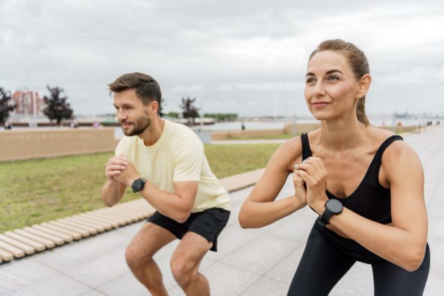 Fitness enthusiasts performing squats outdoors on a cloudy day near a waterfront park