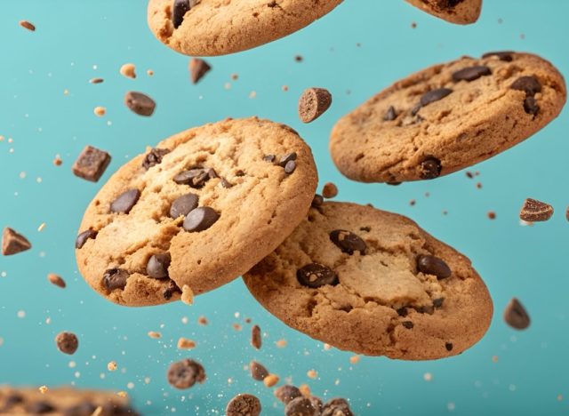 Falling chocolate cookies on color background. Crispy chocolate chip cookie flying or levitating.