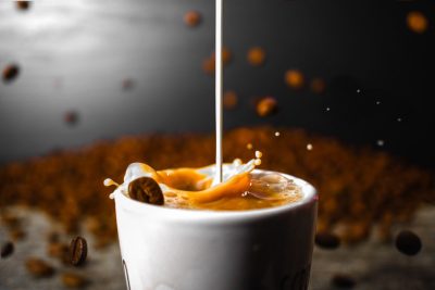 Coffee Beans falling while creamer mixes with coffee