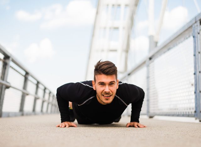 Athlete guy does push-ups on the bridge