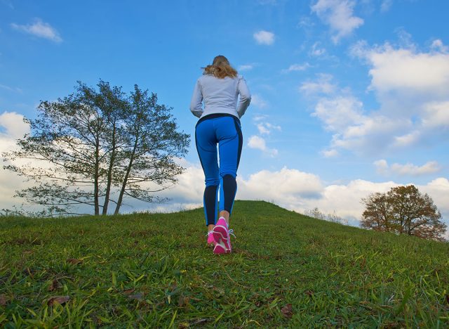 Pretty female going up the hill to clouds with a nice background