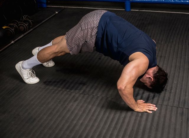 A fit and athletic asian man does pike push-ups at the gym. HIIT or calisthenics workout