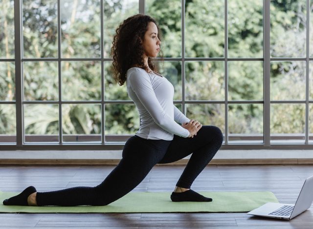Young woman doing front lunges or squat exercise at home