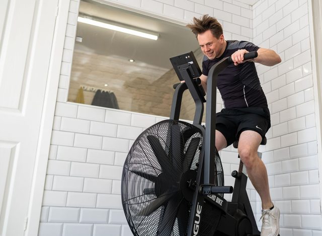 Ipswich Suffolk UK April 03 2022: Sporty and fit young man doing a high intensity workout on an air bike. This works out the upper and lower body at the same time
