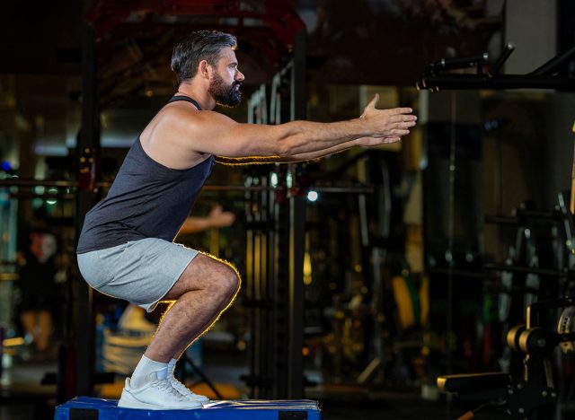 Caucasian man with strong and muscular firm shape is training on leg day by doing advance jump squat for thigh and calf muscle in gym for healthy and strong lower body weight strength