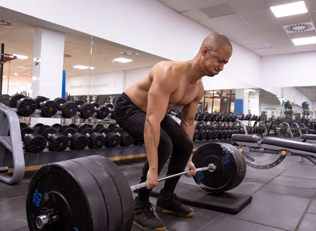 Profile photo with copy space of a strong man doing deadlifts in a gym