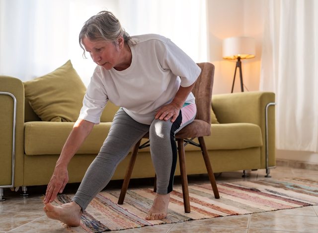 Senior caucasian woman doing doing yoga at home on sofa