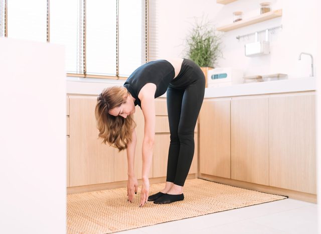 smiling woman stretching down improve movement. gorgeous fitness woman putting hands touching legs for stretching body before workout. happy pretty woman warming up reduce muscle tension for exercise.