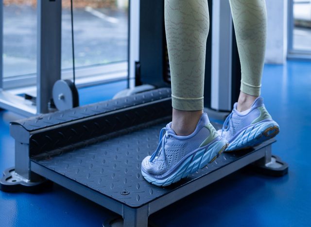 Close up of a sportswoman's legs using a calf raise machine, highlighting her lower body strength and dedication to fitness in a modern gym environment