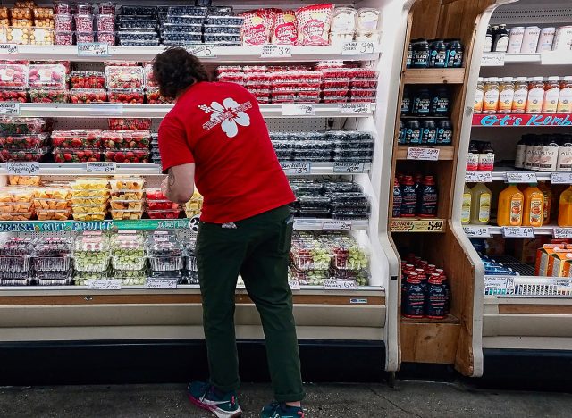 Trader Joe's employee stocking shelves with packaged fruit