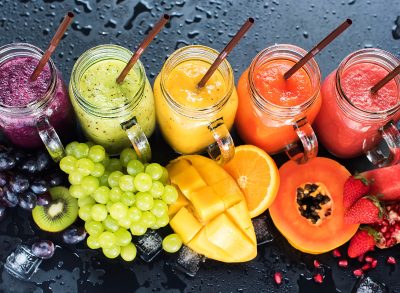 Fresh Color Juices Smoothie Violet Green Yellow Orange Red from Tropical Fruits Kiwi Water Melon Strawberry Apple Orange Banana Pine Apple Mango Pomegranate Grape Bottles Rainbow Dark Background