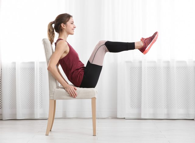 Young woman exercising with chair indoors. Home fitness
