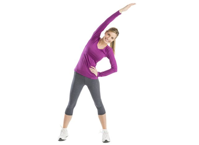 Full length portrait of happy young woman with arms raised doing stretching exercise against white background