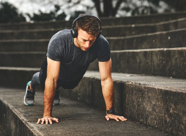 Young fit man doing push-ups outdoors on concrete steps