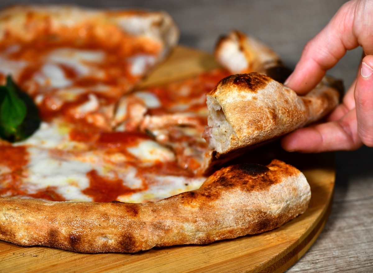 A,Girl’s,Hand,Takes,A,Slice,Of,High dough,Neapolitan,Margherita