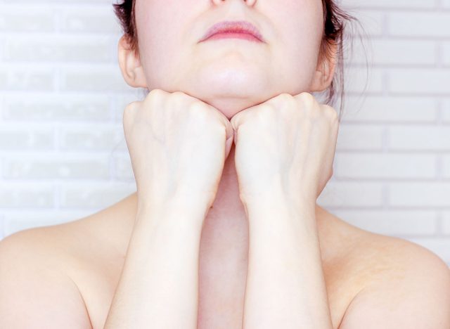 Young caucasian woman touching her face with hands doing face fitness exercises. Facial lifting and massage concept