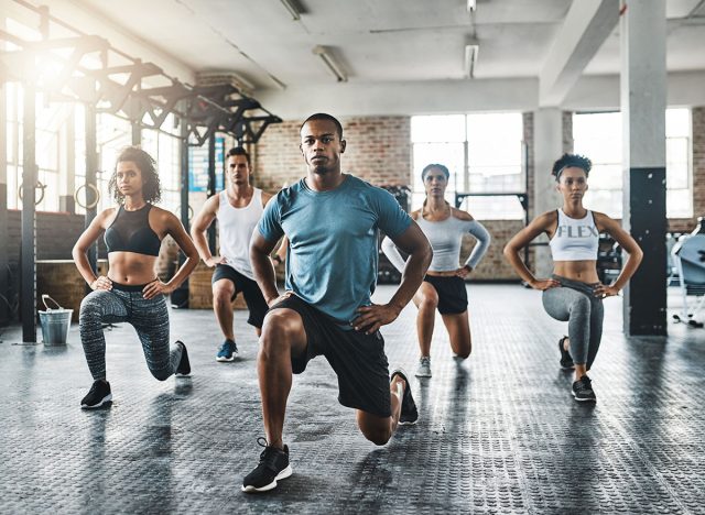 Every step taken towards fitness pays off. Shot of a group of young people doing lunges together during their workout in a gym.