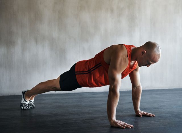 Workout, muscular and man doing push up for exercise, health performance and sports training for muscle building. Bodybuilding mockup, healthy gym body and strong person doing studio floor pushup
