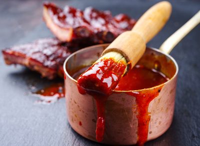 Hot and spicy barbecue sauce in a casserole with spare ribs in background
