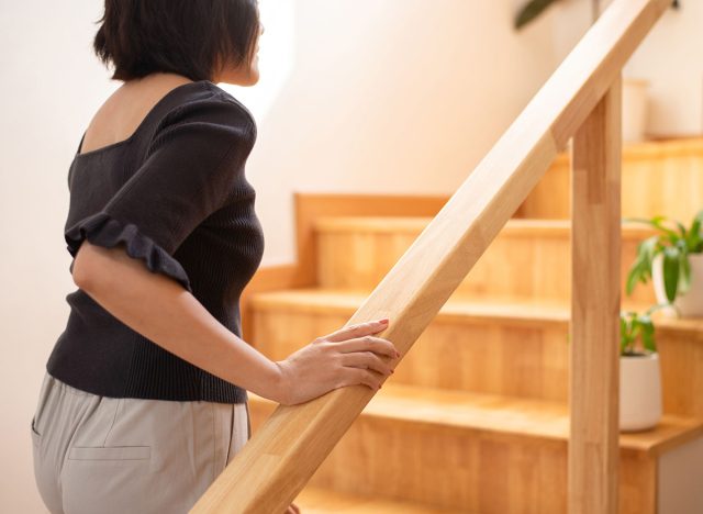 Woman hands holding on to the railing while walking up the stairs at home
