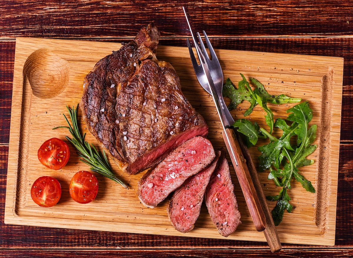 Ribeye,Steak,With,Arugula,And,Tomatoes,On,Dark,Wooden,Background.