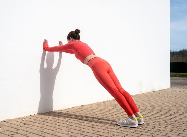 Sporty woman doing push off exercises against a wall