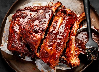 Hot grilled spare ribs from a summer BBQ served on a plate with sauce. Top view.