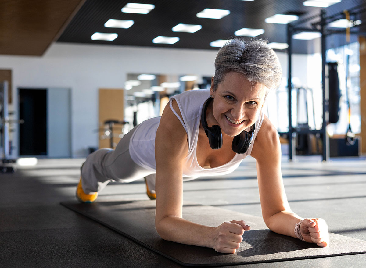 Smiling fitness An elderly gray-haired senior pensioner stand in plank position doing push