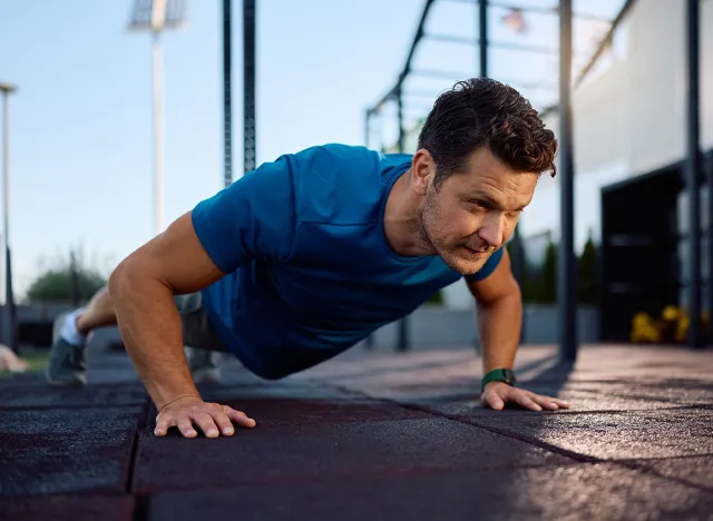 Male athlete exercising push-ups during strength training in outdoor gym. Copy space.