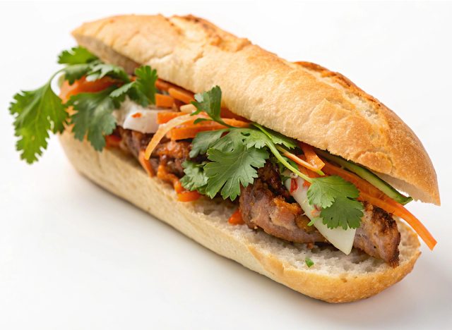 Delicious Vietnamese banh mi sandwich with pork, vegetables, and sauce. Perfect for a quick and tasty meal. Isolated on white background for easy use.