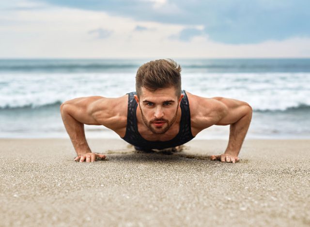 Workout Exercise. Closeup Of Healthy Handsome Active Man With Fit Muscular Body Doing Push Ups Exercises. Sporty Athletic Male Exercising At Beach, Training Outdoor. Sports And Fitness Concept