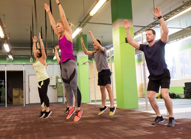 fitness, sport and healthy lifestyle concept - group of people exercising and jumping in gym