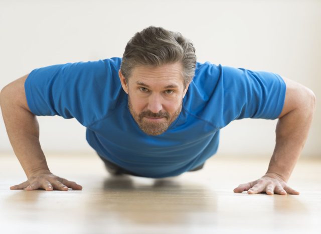 Portrait of mature man doing push-ups on floor at home