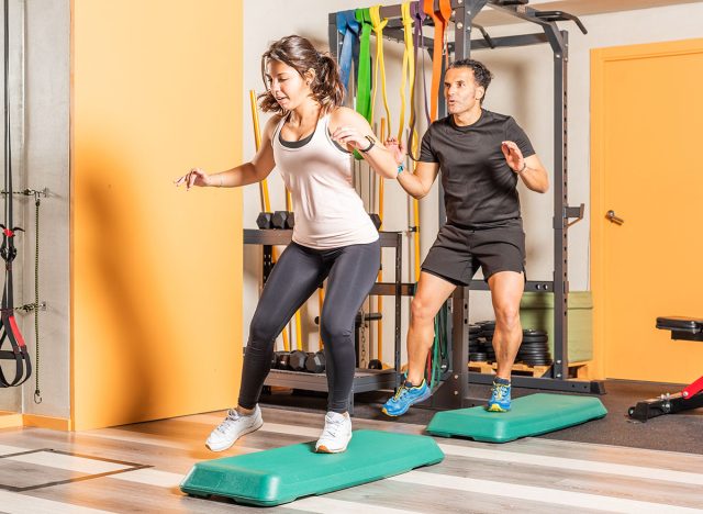 Athlete woman and man doing lateral step up jumps in health club