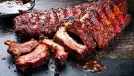 Barbecue pork spare loin ribs St Louis cut with hot honey chili marinade burnt as closeup on an old rustic board