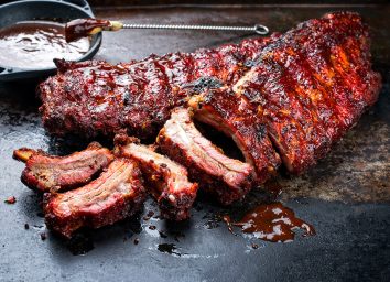 Barbecue pork spare loin ribs St Louis cut with hot honey chili marinade burnt as closeup on an old rustic board
