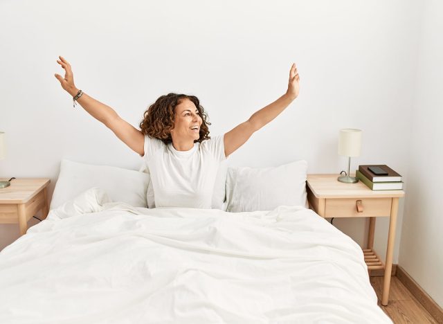 Mature hispanic woman waking up from bed at the bedroom
